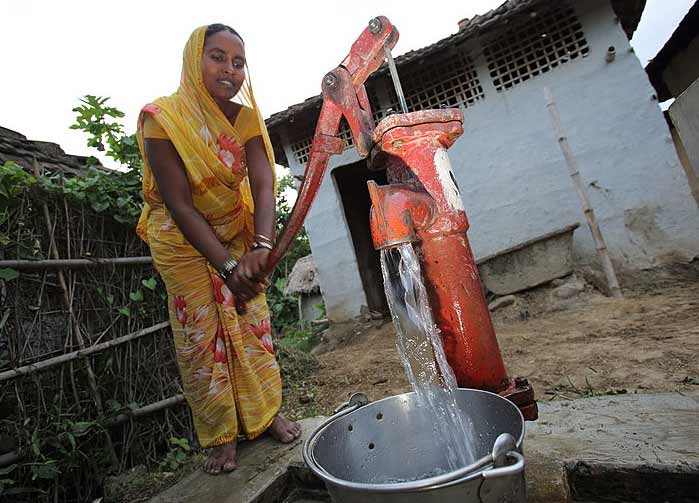 Woman pumps water from a well