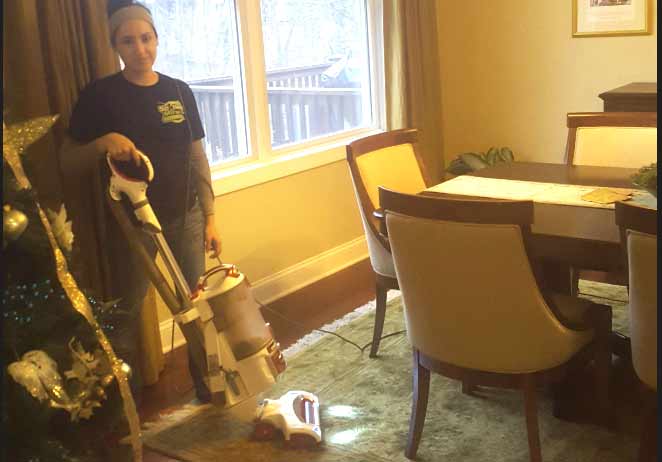 Woman vacuumes a rug