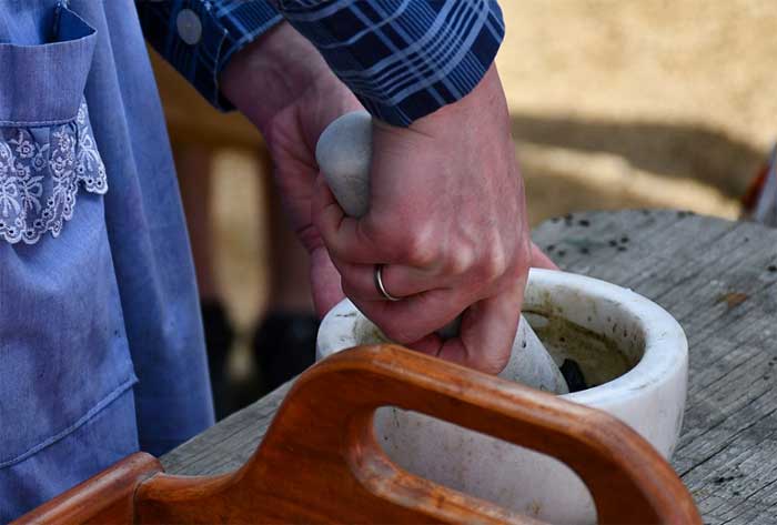 woman grinding herbs with a mortar and pestle